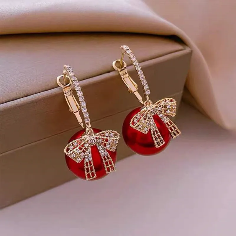 Elegantes pendientes de perlas rojas con lazo brillante