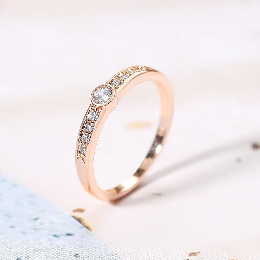 Bague en or rose avec pierre centrale ronde et pavage étincelant