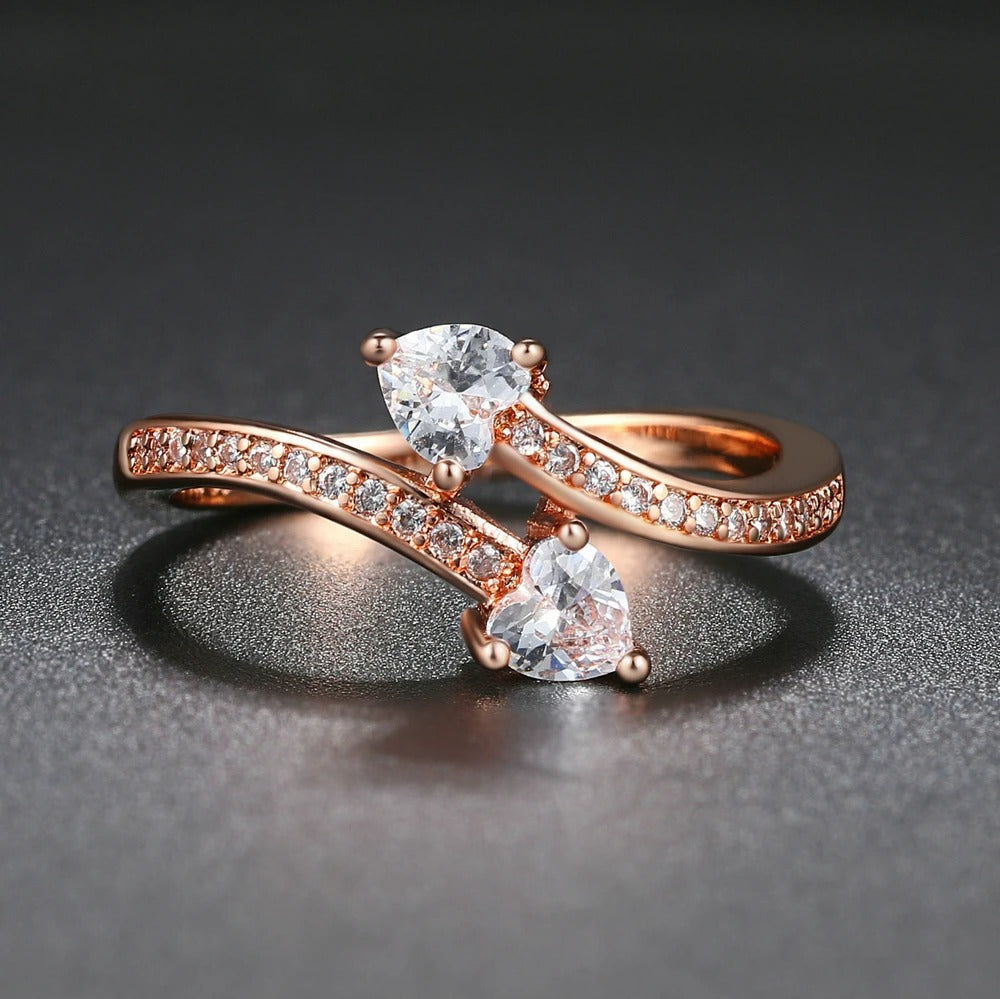 Anillo de oro rosa con dos corazones de cristales y banda de cristales pavimentados