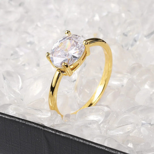 Anillo dorado brillante con piedra ovalada transparente y diseño sencillo
