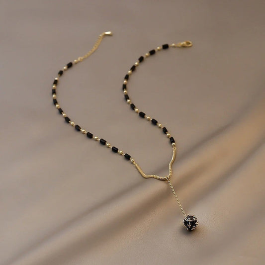 Collier vintage doré et noir à perles pendantes